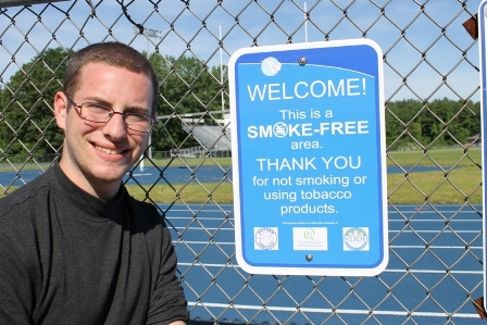 Smoke_Free_Sign_Student student in front of smoke free area sign